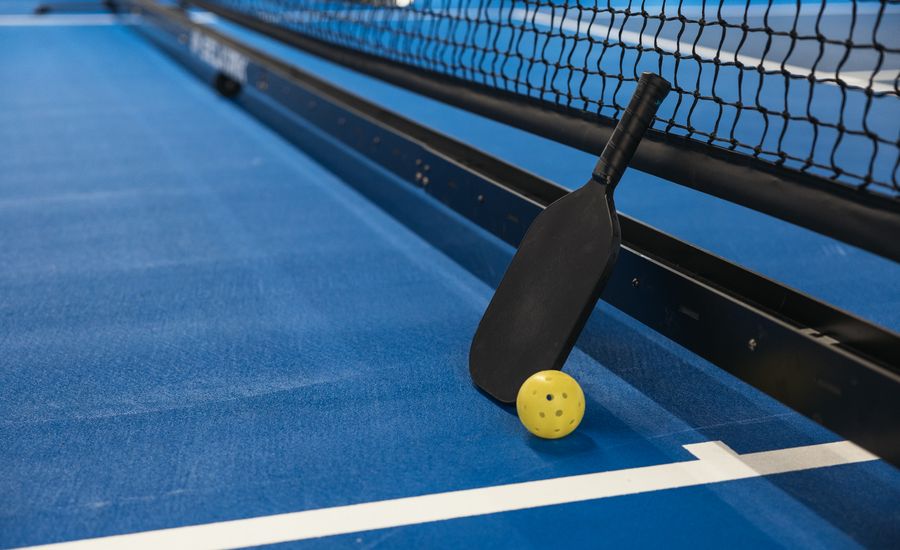 Raquette et balle de pickleball sur un terrain bleu